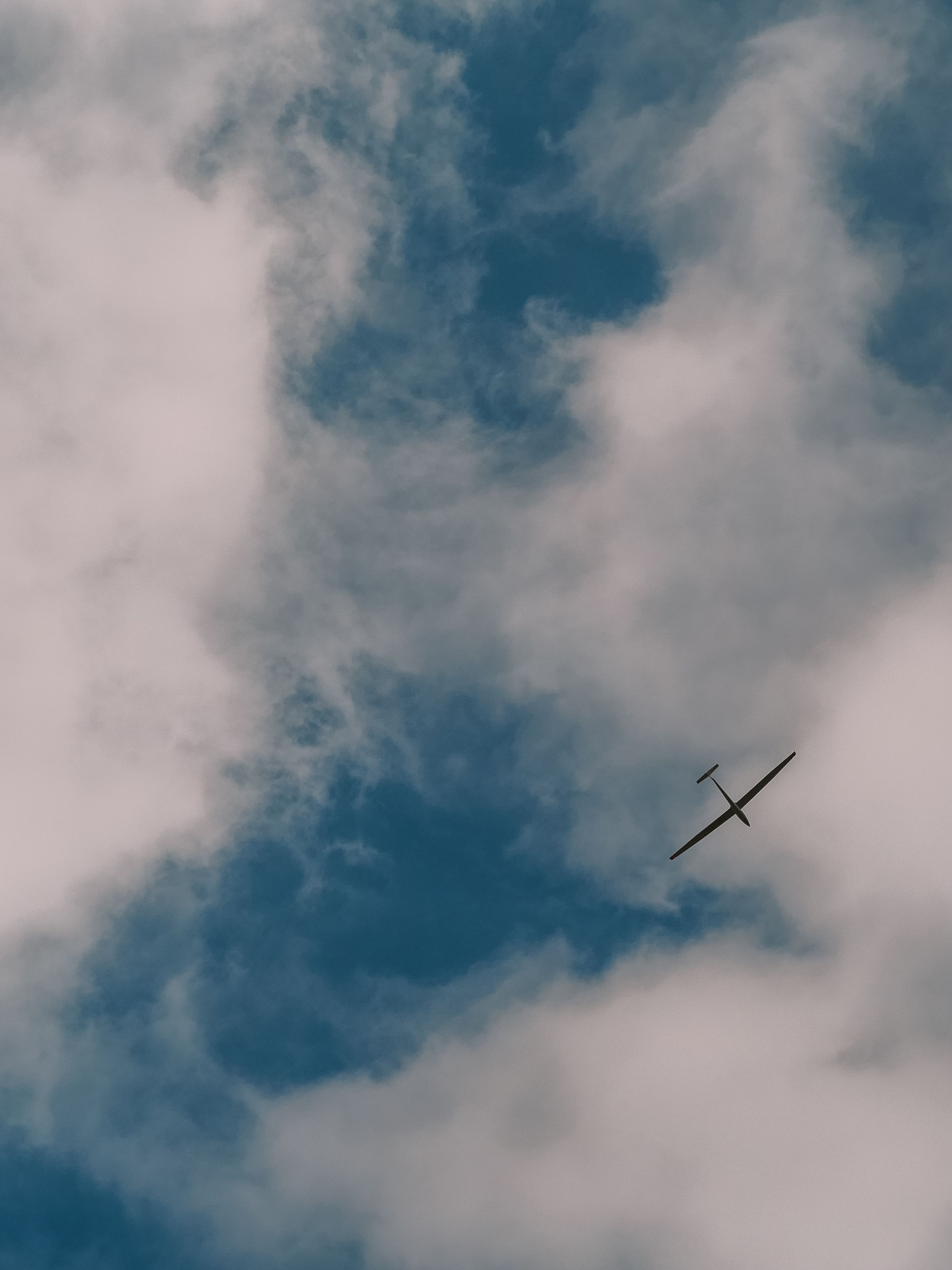 Segelflugzeug klein zwischen mächtigen Wolken